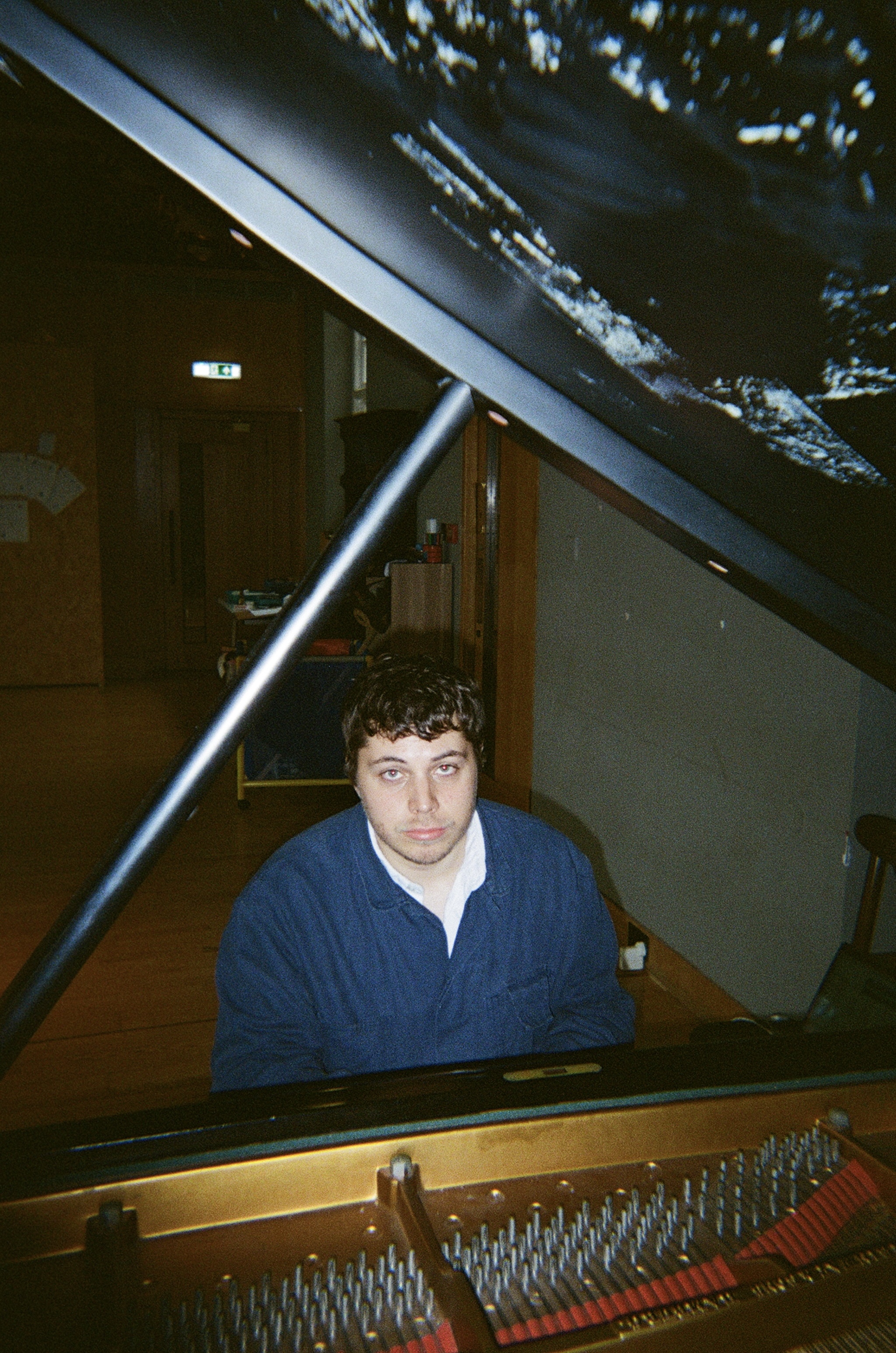 Brandon Hopkins seated at a grand piano with the lid open